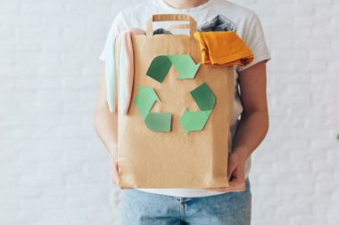 Girl holding paper bag with old clothes for recycling